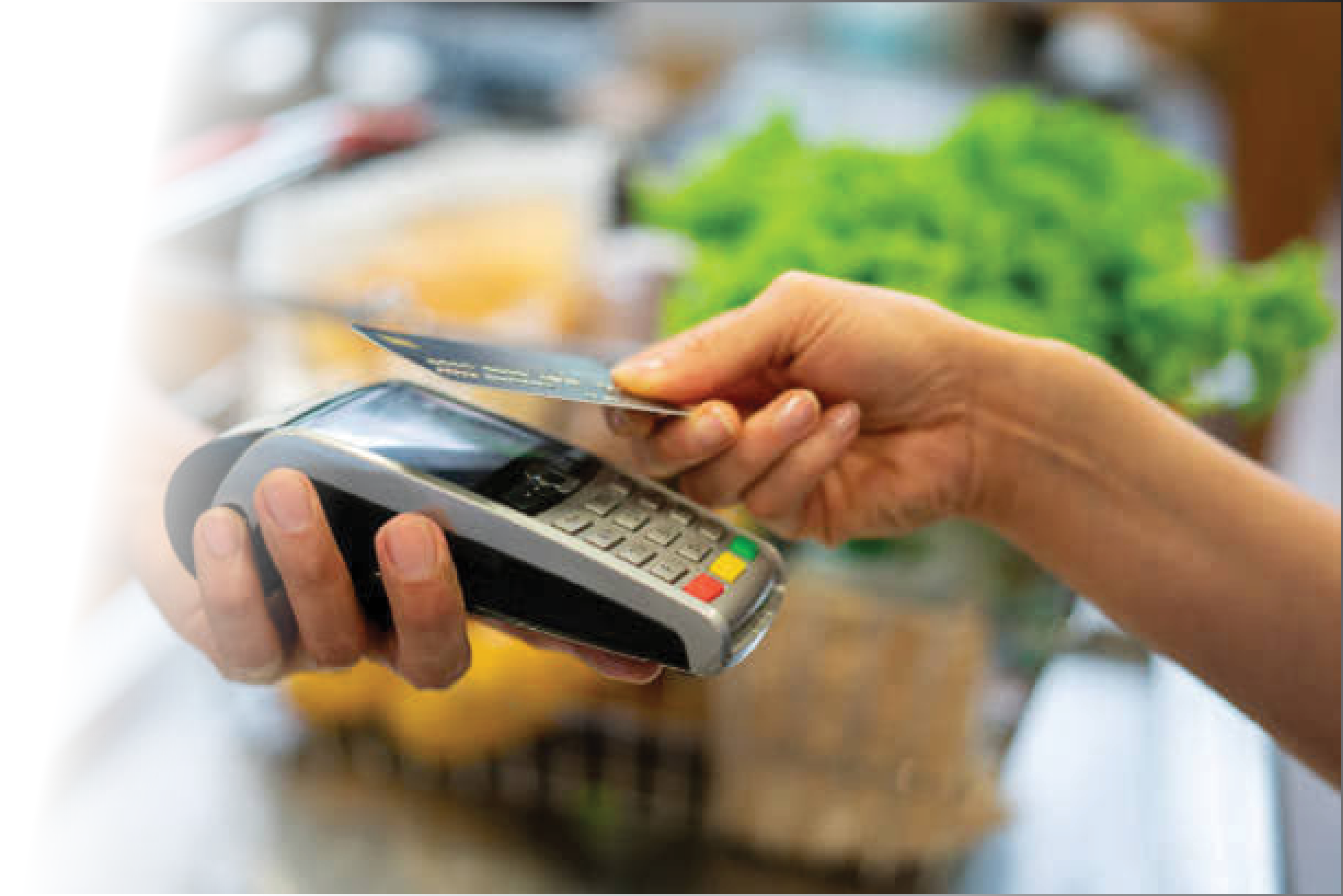 A store clerk holding out a credit card machine for a customer to make a contactless payment.