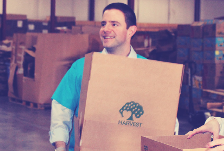 Man smiling while holding a Harvest Hope food bank box.